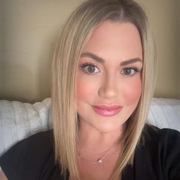 A woman with blonde hair and pink lipstick is smiling for the camera.